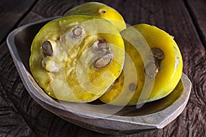 Araza fruits in a wooden bowl on rustic background photo