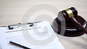 Arbitration agreement document on table, gavel lying on sound block, dispute