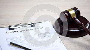 Arbitration agreement document on table, gavel lying on sound block, dispute photo
