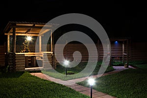 Arbor and barbecue in backyard at night