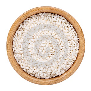 Arborio short-grain rice in wooden bowl isolated on white. Top view