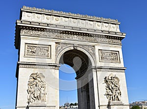 Arc de Triomphe close-up from Champs Elysees with blue sky. Paris, France.