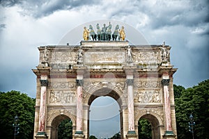 Arc de triomphe du carrousel in paris, france. Arch monument and green trees on cloudy sky. Architectural symbol of peace victory