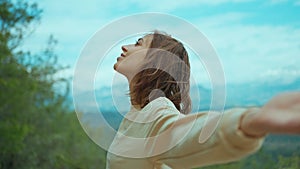 Arc Shot of Young Woman Standing outdoors on mountains background and Turning around with Her Arms Spread Wide and Eyes