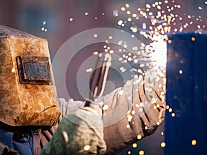 Arc welder worker in protective mask welding metal construction