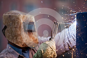 Arc welder worker in protective mask welding metal construction