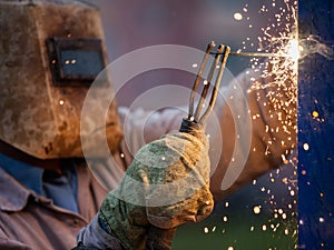 Arc welder worker in protective mask welding metal construction