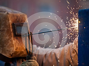 Arc welder worker in protective mask welding metal construction