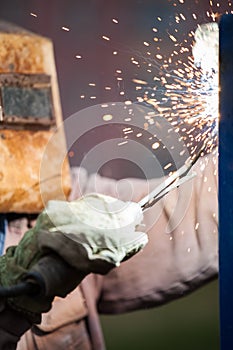 Arc welder worker in protective mask welding metal construction