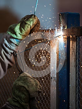 Arc welder worker in protective mask welding metal construction