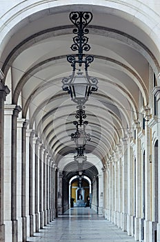Arcade with vaulted ceiling and iron lamps in the building at Praca do Comercio in Lisbon, Portugal