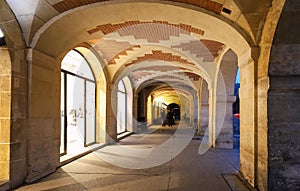 The arcades of place des Vosges in Paris , France.