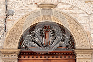 Arch above door made of wrought iron spokes and stone surround