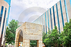 Arch of ancient Bab Alfurdhah Gate surrounded by modern office buildings on the street of Al-Balad, Jeddah, Saudi Arabia