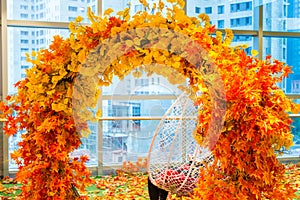 Arch with artificial orange fall foliage with a girl sitting on hanging chair