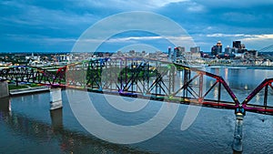 Arch bridge aerial rainbow pride illuminated at night over Ohio River Louisville Kentucky