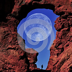 Arch in Canyon Red Rock Formations Silhouette of Hiker with Full Moon in Sky