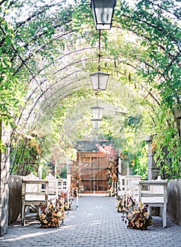 Arch decor ceiling with Garden lanterns over tiled floor with wooden seats, vertical shot