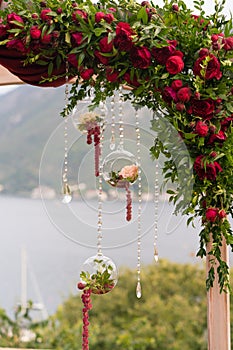 Arch decorated with fresh flowers in dark red tones for the wedding ceremony