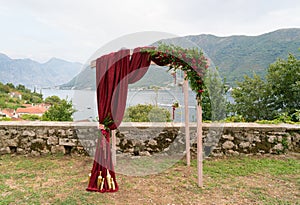 Arch decorated with fresh flowers in dark red tones for the wedding ceremony