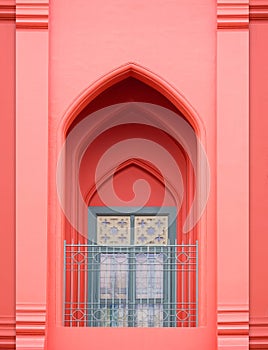 Arch door in Moroccan style with wooden window and wrought iron fence on balcony of vintage old rose building in vertical frame