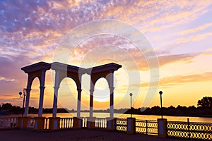 Arch on the embankment on the banks of the Dnieper River at sunset background. Kherson region. Bare pier