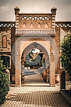 Arch gate in an Moroccan building. Arabic architectureof a palace in the sahara desert. Pathway with arch and plants. Traditional