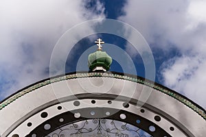 Arch and green dome with a Golden cross on blue sky between the