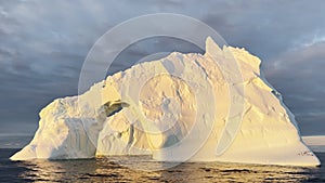 Arch in a huge iceberg, high breakaway glacier drifts in the southern ocean off the coast of Antarctica at sunset, the