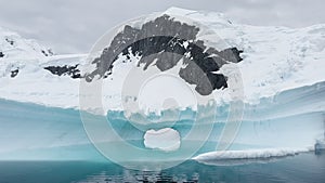 Arch in a huge iceberg, high breakaway glacier drifts in the southern ocean off the coast of Antarctica at sunset, the