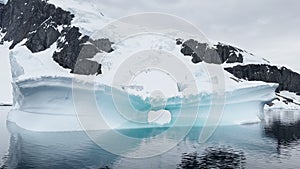 Arch in a huge iceberg, high breakaway glacier drifts in the southern ocean off the coast of Antarctica at sunset, the