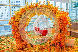 Arch with orange fall foliage with hanging white chair.