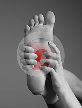 Arch pain caused by inflammation, overuse, plantar fascia injury. Woman hands holding foot with red point. Black and