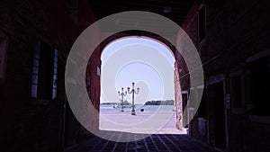 Arch passway to waterfront and sailing ship on sea in Venice