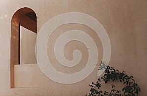 An arch-shaped window in the wall of the building. Light shadows on the wall.