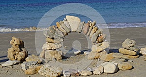 Arch of stones against sky. Balancing stones on sand. Zen Style Stones by the Sea