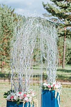 Arch for the wedding ceremony decorated with flowers and dry branches. Outdoor Wedding ceremony scene