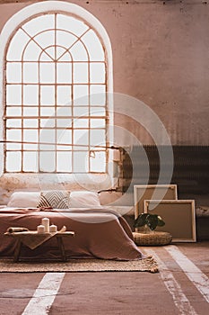 Arch window in a wabi sabi bedroom interior with a bed and iron radiator photo