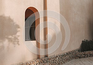 An arch window in the wall of the arabic building. Summer floral shadows and sunlight.