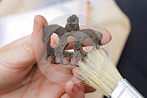 An archaeologist cleans a medieval bronze pendant in the animal style