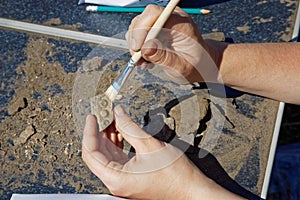 Archaeologist`s hands clear the find from dust