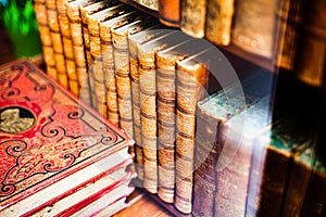 Archaic prop hardcover books aligned on a wooden shelf closeup. Old literature reading and collecting antique shop abstract