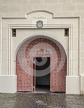 Arched  antique wooden door  with  black iron ornaments in a stone wall. Basilica Minor of Saint Benedict in Hronsky Benadik