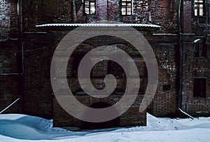 Arched decorative brick porch of old house. Ancient brick mansion at night. Fragment of the facade