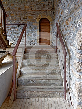 Arched door and wooden stairs of old stone building