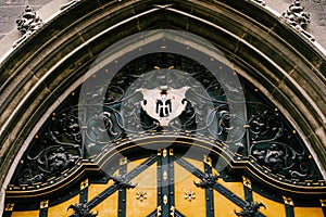 Arched door with wrought iron decor elements and coat of arms with an angel in an old building