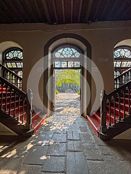 Arched doorway with intricate windows leading to a sunny courtyard