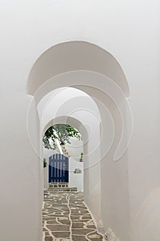 Arched doorways leading to a blue door. Traditional architecture of local villages at Paros island in Greece.