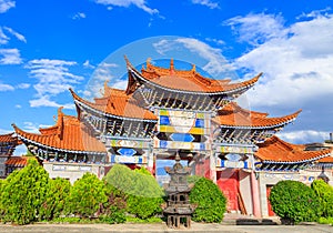 Arched entrance of Chinese temple under blue sky and white clou