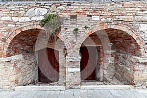 Arched entrance with thick medieval walls to a building in the Bagno Vignoni. Tuscany, Italy